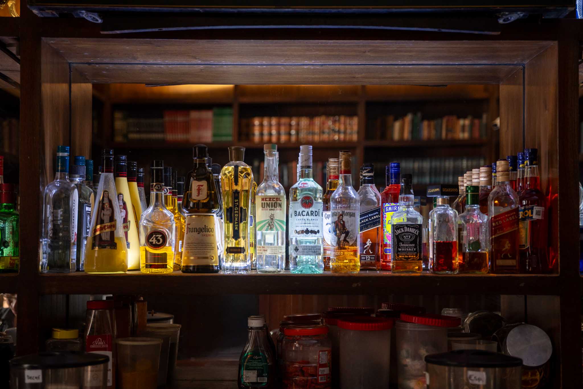 Barra de bar iluminada con botellas en la biblioteca del hotel