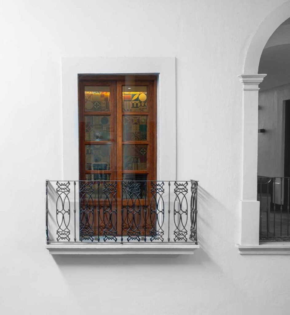 Balcón interior con herrería sobre muro blanco del hotel
