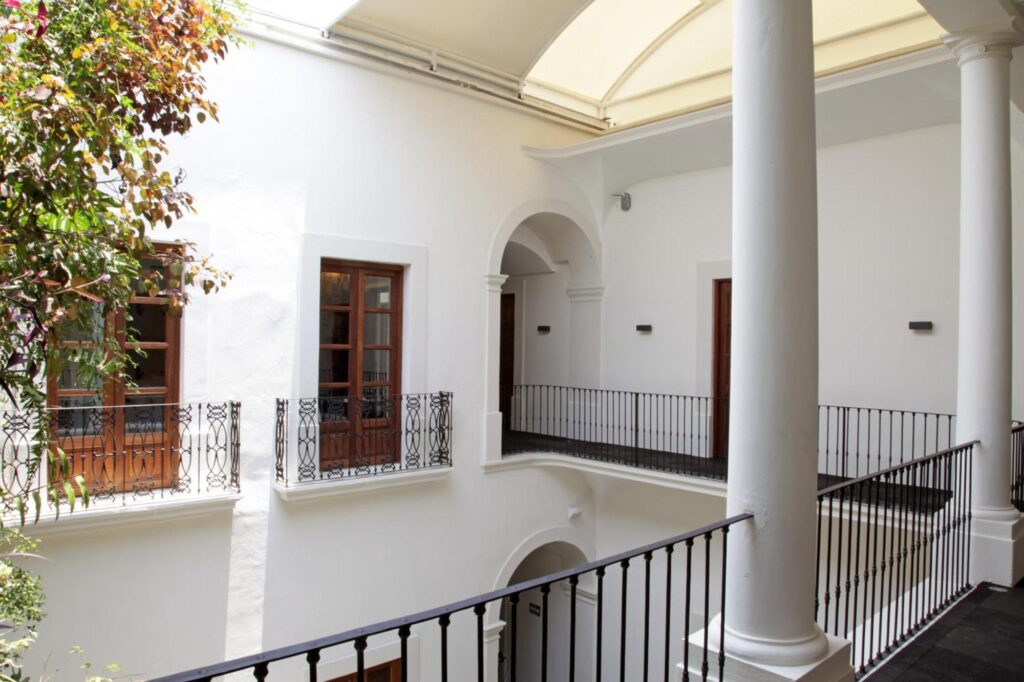 Corredor interior con columnas y barandales de herrería del hotel